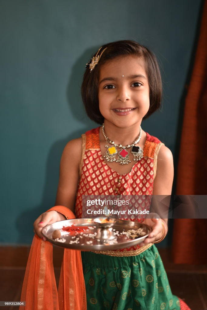 Young girl in traditional Indian attire holding pooja thali