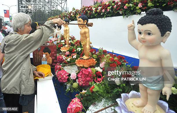 Taiwanese woman showers a Buddha statue with water in a symbolic gesture to clean the spirit of people, during a gathering in Taipei on May 9, 2010....