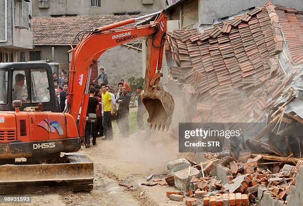 Chinese authorities carry sticks as they stand guard while workers demolish houses which are claimed illegal by the local government in Wuhan,...