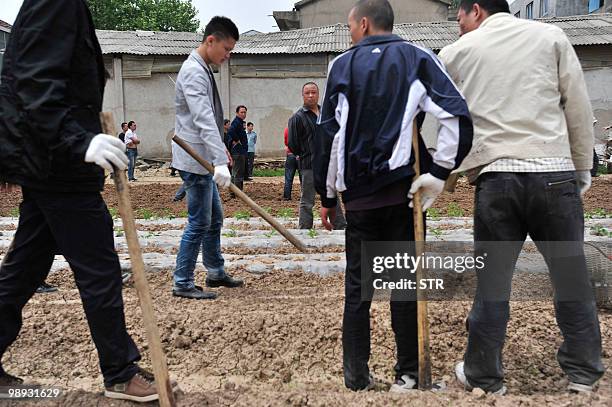 Chinese authorities carry sticks as they stand guard while workers demolish houses which are claimed illegal by local government in Wuhan, central...