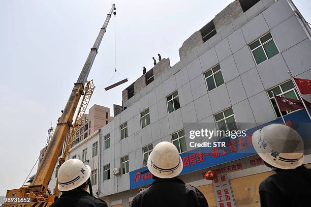 Chinese authorities look on as they stand guard while workers demolish buildings which are claimed illegal by local government in Wuhan, central...