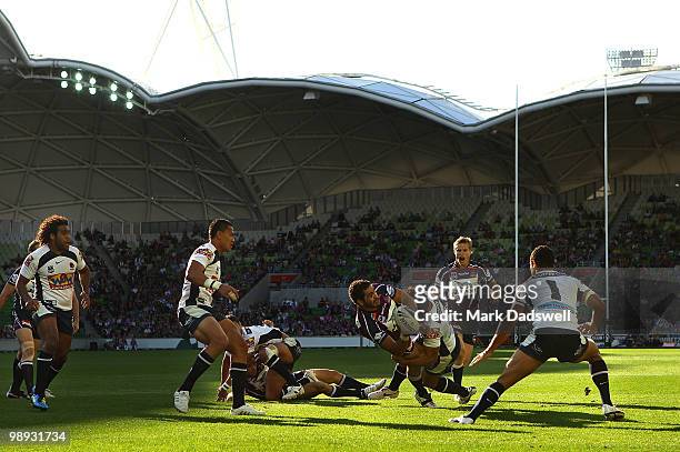 Greg Inglis of the Storm throws a pass as he is tackled during the round nine NRL match between the Melbourne Storm and the Brisbane Broncos at AAMI...