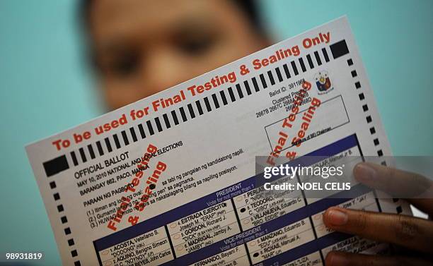 School teacher checks the filled ballot paper during the final testing and sealing of automated election counting machines a day before the election,...