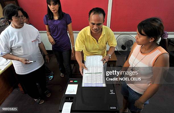 Mock voter cast his ballot to a Precint Count Optical Scanner during the final testing and sealing of automated election counting machines a day...