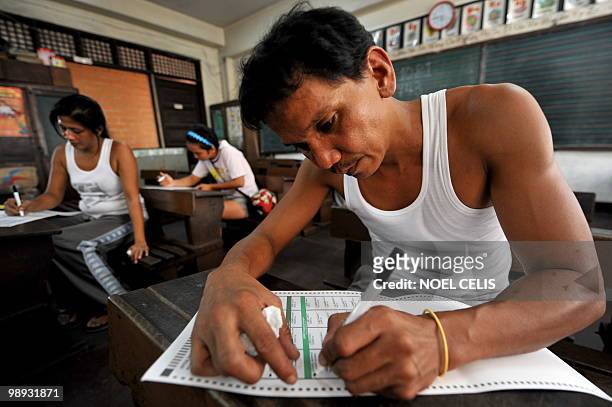 Mock voters fill in their ballots during the final testing and sealing of automated election counting machines a day before the election, in a public...