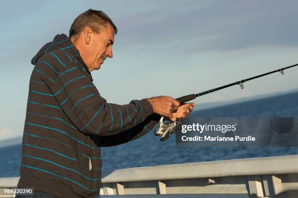 a man fishing off the edge of a pier - angel brinks stock-fotos und bilder