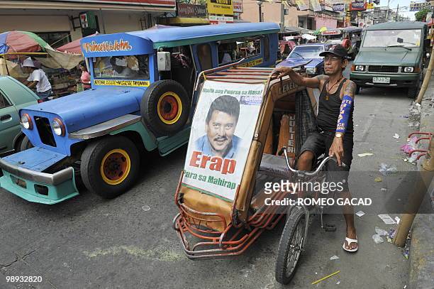 Filipino pedicab driver Raul Vergara waits for passengers on his mini public transport vehicle decorated with a portrait of presidential candidate,...