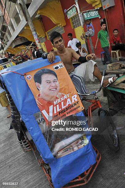 Filipino pedicab driver Remboy Rayna waits for passenger on his mini public transport vehicle decorated a portrait of presidential candidate Manuel...