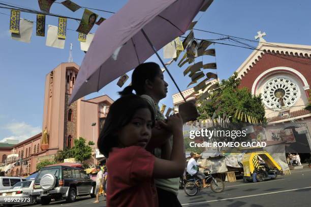 Political campaign posters of various candidates hang on street cables outside two Roman Catholic churches in Manila on May 9, 2010. About 40 million...