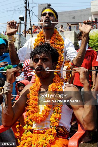 Indian Hindu devotees walk with trident rods piercing their tongues known as Trishula while taking part in a procession held to honour the Hindu...