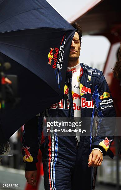 Mark Webber of Australia and Red Bull Racing is poked in the face by an errant team umbrella on the way to the grid before the start of the Spanish...