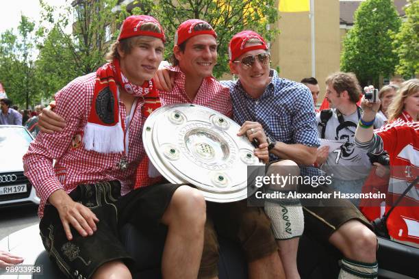 Bastian Schweinsteiger and his team mates Mario Gomez as well as Holger Badstuber celebrate the German championship with the trophy on the way to the...