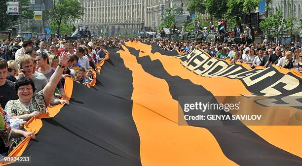 People hold a Saint-George banner, commemorating the WWII heroes of the eastern front, during a Victory Day parade in Kiev on May 9 marking the 65th...