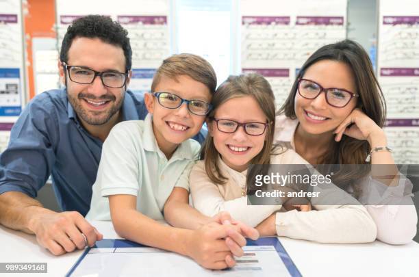 gelukkige familie proberen op glazen op de optische winkel - 2018 glasses stockfoto's en -beelden