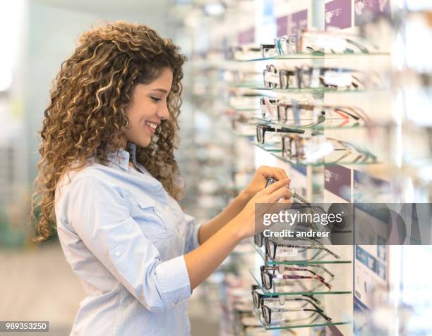 woman buying glasses at the optical shop - lens optical instrument stock pictures, royalty-free photos & images