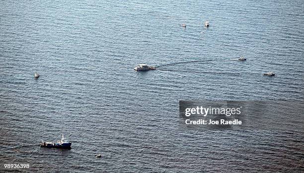 Boats pull an oil boom behind them as they skim the oil from the surface near where the Deepwater Horizon oil platform sank as work continues to...