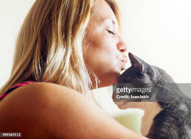 young woman kissing with her cat - ivanjekic stock pictures, royalty-free photos & images