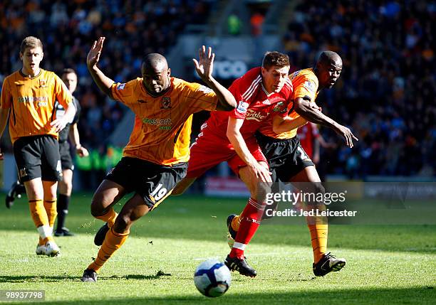 Steven Mouyokolo and George Boateng of Hull City sandwich Steven Gerrard of Liverpool during the Barclays Premier League match between Hull City and...