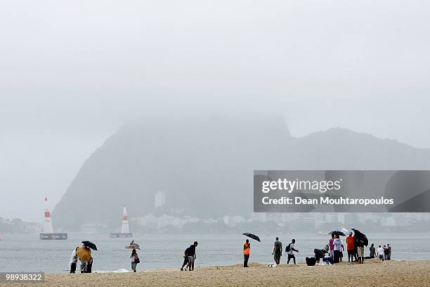 Fans wait on the beach in the rain as Sugar Loaf Mountain during the Red Bull Air Race Day on May 9, 2010 in Rio de Janeiro, Brazil.