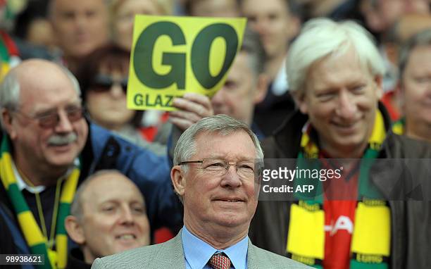 Supporters hold posters opposing Manchester United's US owner Malcolm Glazer behind United manager Sir Alex Ferguson's head before the English...