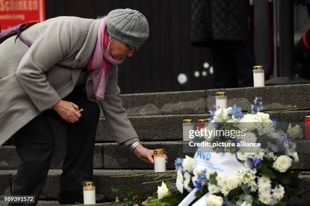 Pedestrian places a candle next to a memorial commemorating the victims of a terror attack on the Christmas market on Breitscheidsplatz in Berlin,...