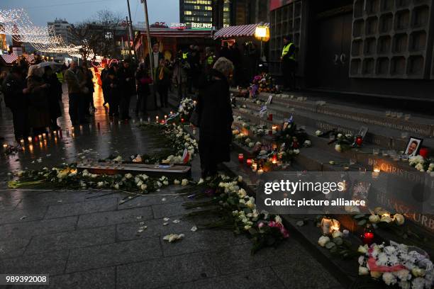 Pedestrians place flowers, pictures and candles next to a memorial commemorating the victims of a terror attack on the Christmas market on...