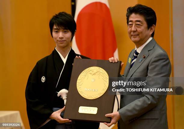 Japanese Prime Minister Shinzo Abe and Japanese figure skater Yuzuru Hanyu pose with People's Honor Award trophy during its presentation ceremony at...