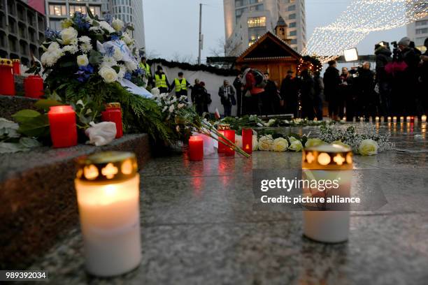 Pedestrians place flowers, pictures and candles next to a memorial commemorating the victims of a terror attack on the Christmas market on...