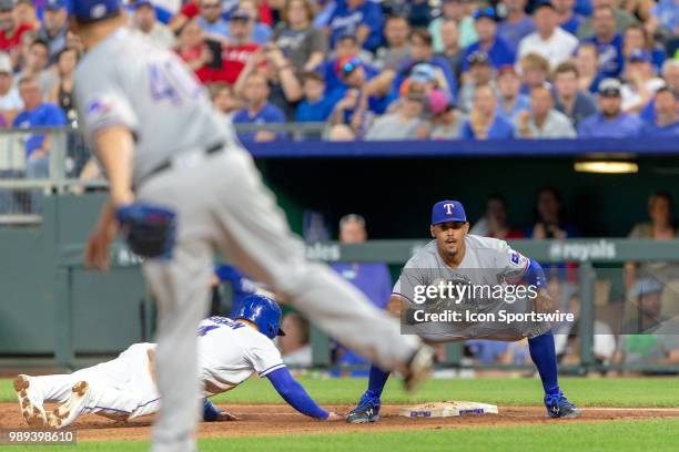 Texas Rangers first baseman Ronald Guzman reaches for a throw as Kansas City Royals left fielder Alex Gordon dives back to first base during the MLB...