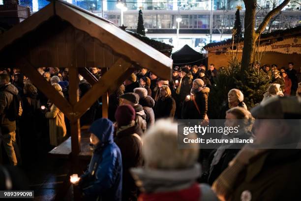 Several people stand at the Christmas market on Breitscheidsplatz to commemorate the victims of the terror attack one year ago, in Berlin, Germany,...