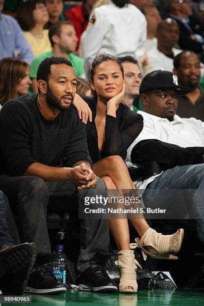 Singer John Legend and model Christine Teigen watch the Boston Celtics play against the Cleveland Cavaliers in Game Four of the Eastern Conference...