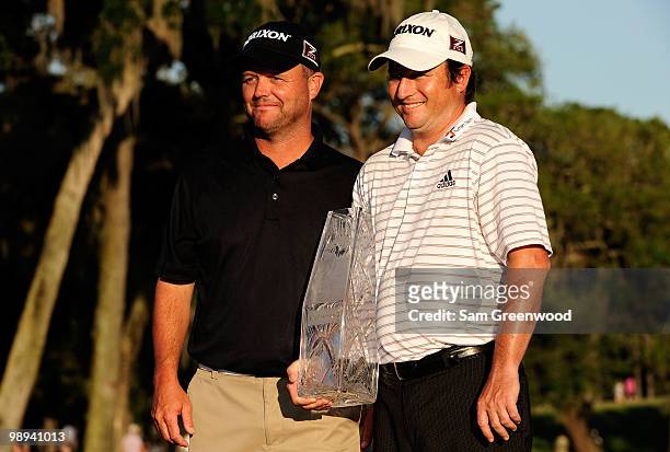 Tim Clark of South Africa smiles with his caddie Steve Underwood while holding the trophy after winning THE PLAYERS Championship held at THE PLAYERS...