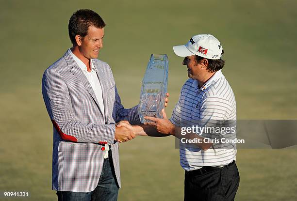 Defending champion Henrik Stenson of Sweden hands the tournament trophy to Tim Clark of South Africa after Clark won THE PLAYERS Championship on THE...