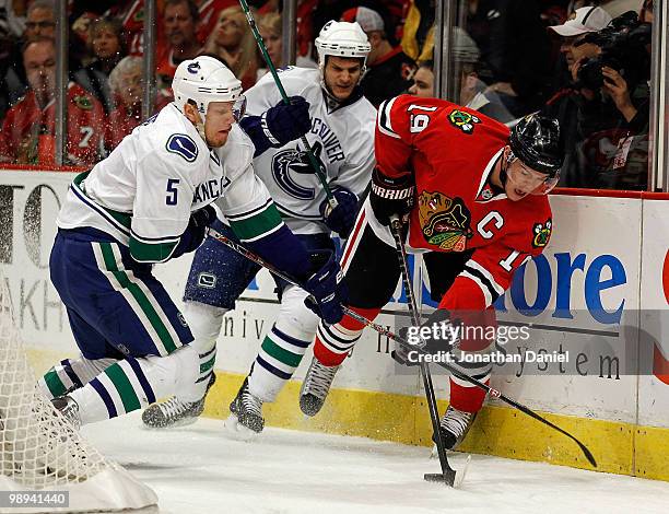 Jonathan Toews of the Chicago Blackhawks controls the puck under pressure from Christian Ehrhoff and Kevin Bieksa of the Vancouver Canucks in Game...