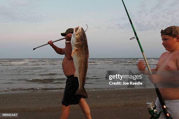 Charlie Wyers carries a fish that his son Zachary Wyers caught in the gulf waters as efforts continue to contain the massive oil spill on May 9, 2010...