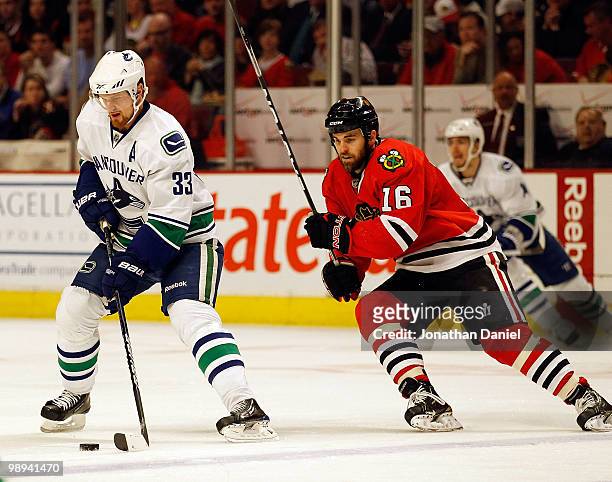 Henrik Sedin of the Vancouver Canucks moves across the ice with the puck as Andrew Ladd of the Chicago Blackhawks closes in in Game Five of the...