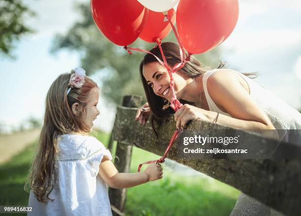 giovane donna con bambino in abito bianco con palloncini colorati all'aperto - mamma bambina palloncino bianco foto e immagini stock