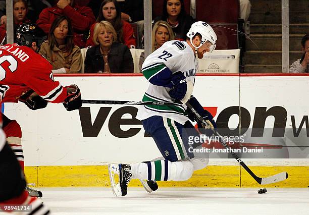 Daniel Sedin of the Vancouver Canucks has his legs buckle before he hits the ice as Dave Bolland of the Chicago Blackhawks defends in Game Five of...