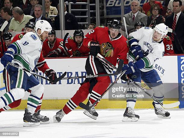 Christian Ehrhoff of the Vancouver Cancuks shoots the puck past Tomas Kopecky of the Chicago Blackhawks and teammate Ryan Johnson at Game Five of the...