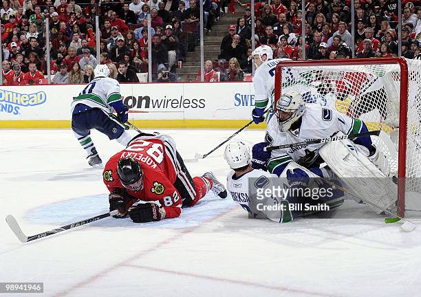 Kevin Bieksa of the Vancouver Canucks slides into Canucks goalie Roberto Luongo as Tomas Kopecky of the Chicago Blackhawks crawls on the ice behind,...