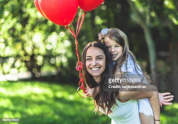 giovane donna con bambino in abito bianco con palloncini colorati all'aperto - mamma bambina palloncino bianco foto e immagini stock