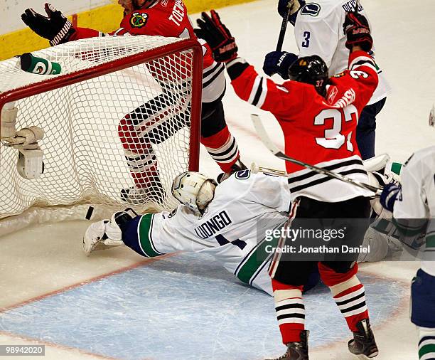 Roberto Luongo of the Vancouver Canucks reaches for the puck on a goal by Jonathan Toews of the Chicago Blackhawks while Adam Burish celebrates in...