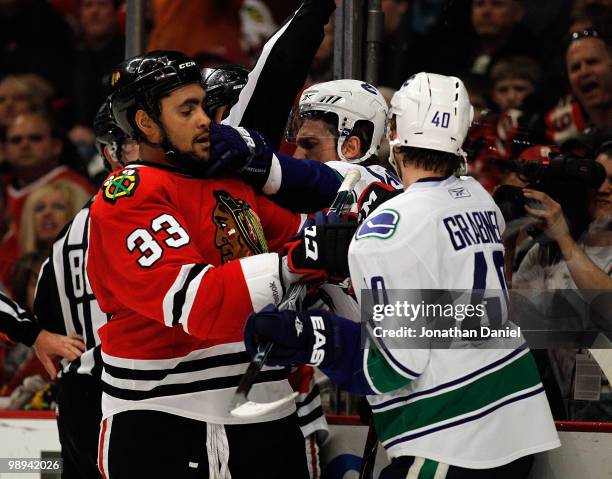 Mikael Samuelsson of the Vancouver Canucks reaches in to smack Dustin Byfuglien of the Chicago Blackhawks in front of Michael Grabner in Game Five of...