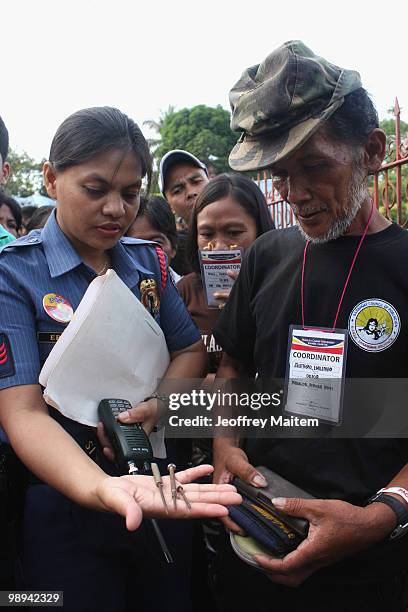 Police office inspects Filipino voters entering a polling center to cast votes on May 10, 2010 in the southern town of Kiamba, Sarangani Province....
