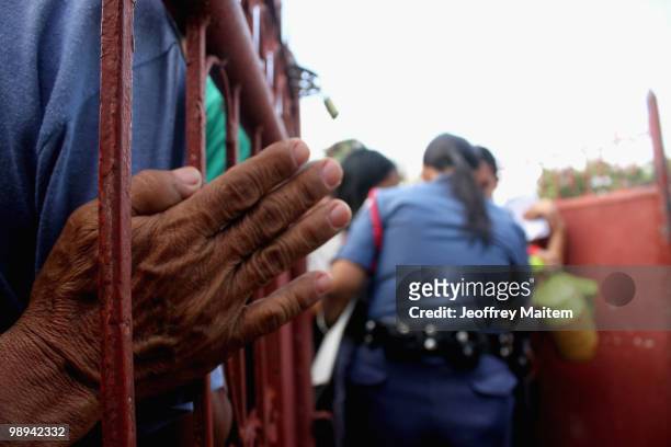 Police office inspects Filipino voters entering a polling center to cast votes on May 10, 2010 in the southern town of Kiamba, Sarangani Province....
