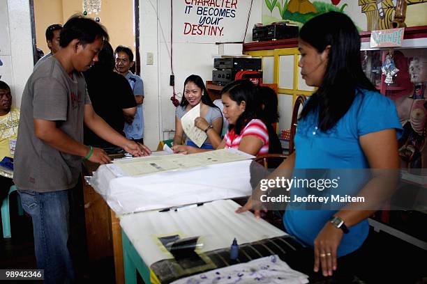 Filipino voters recieves their ballots from election Officers before casting their votes at a polling center on May 10, 2010 in the southern town of...
