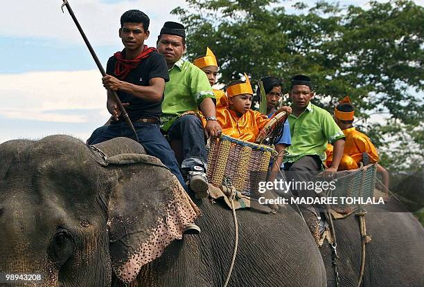 Thai Muslim people sit on elephants during a march part of a local cultural festival in Thailand's southern province of Narathiwat on May 10, 2010....