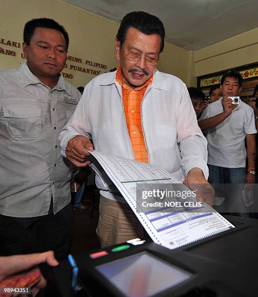 Philippine presidential candidate and former president Joseph Estrada checks his ballot before inserting it to the automated election counting...