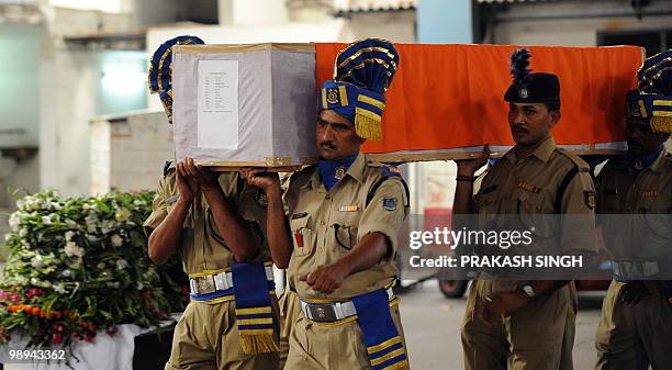 Indian paramilitary officials carry the coffin of a slain Indian Central Reserve Police Force serviceman at the airport in New Delhi on May 10, 2010....