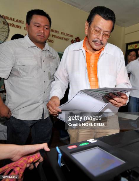 Philippine presidential candidate and former president Joseph Estrada checks his ballot before inserting it to the automated election counting...
